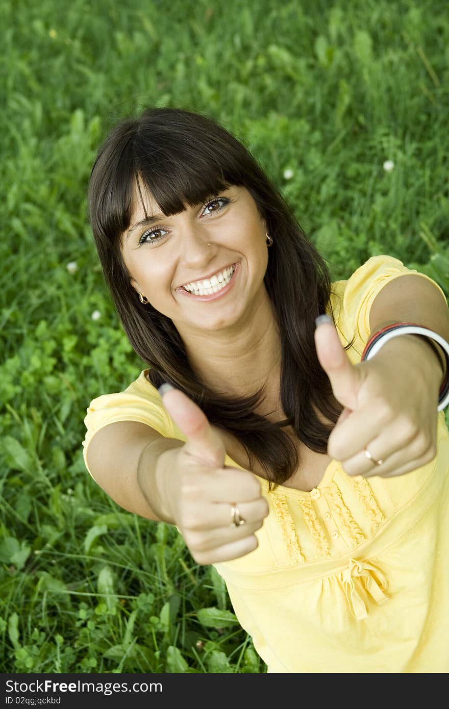 Young beautiful woman is smiling in a park and shows the Thumb Up. Young beautiful woman is smiling in a park and shows the Thumb Up