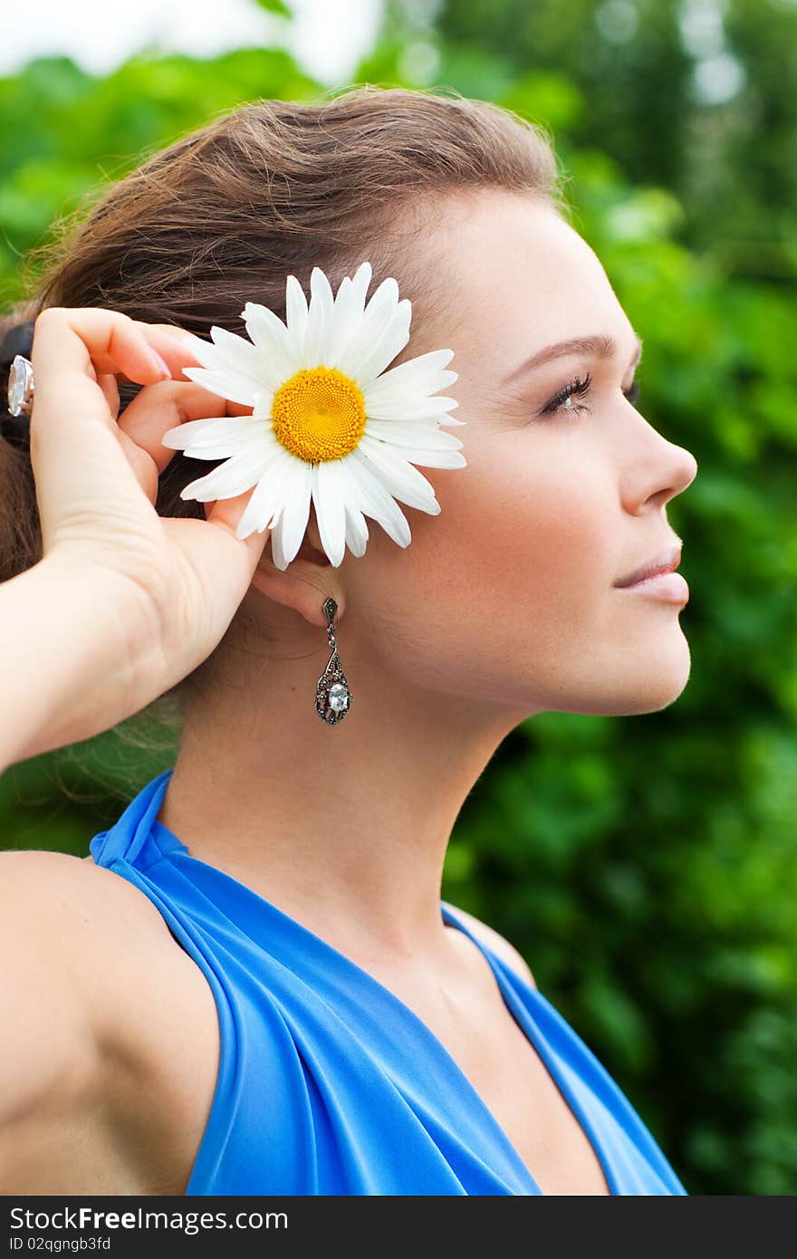 Profile of pretty caucasian young adult with camomile in garden. Profile of pretty caucasian young adult with camomile in garden