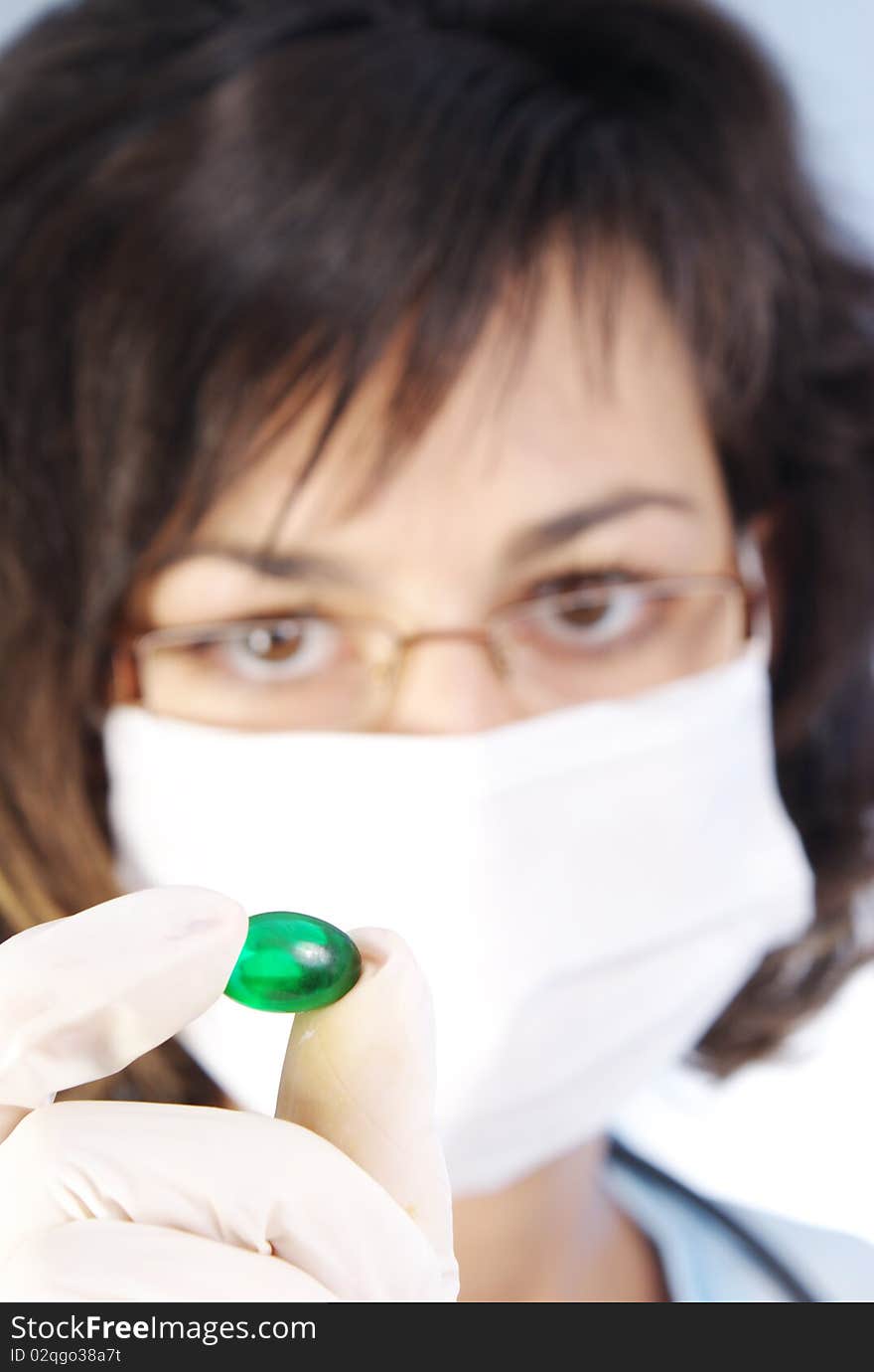 Confident female doctor holding a green pill