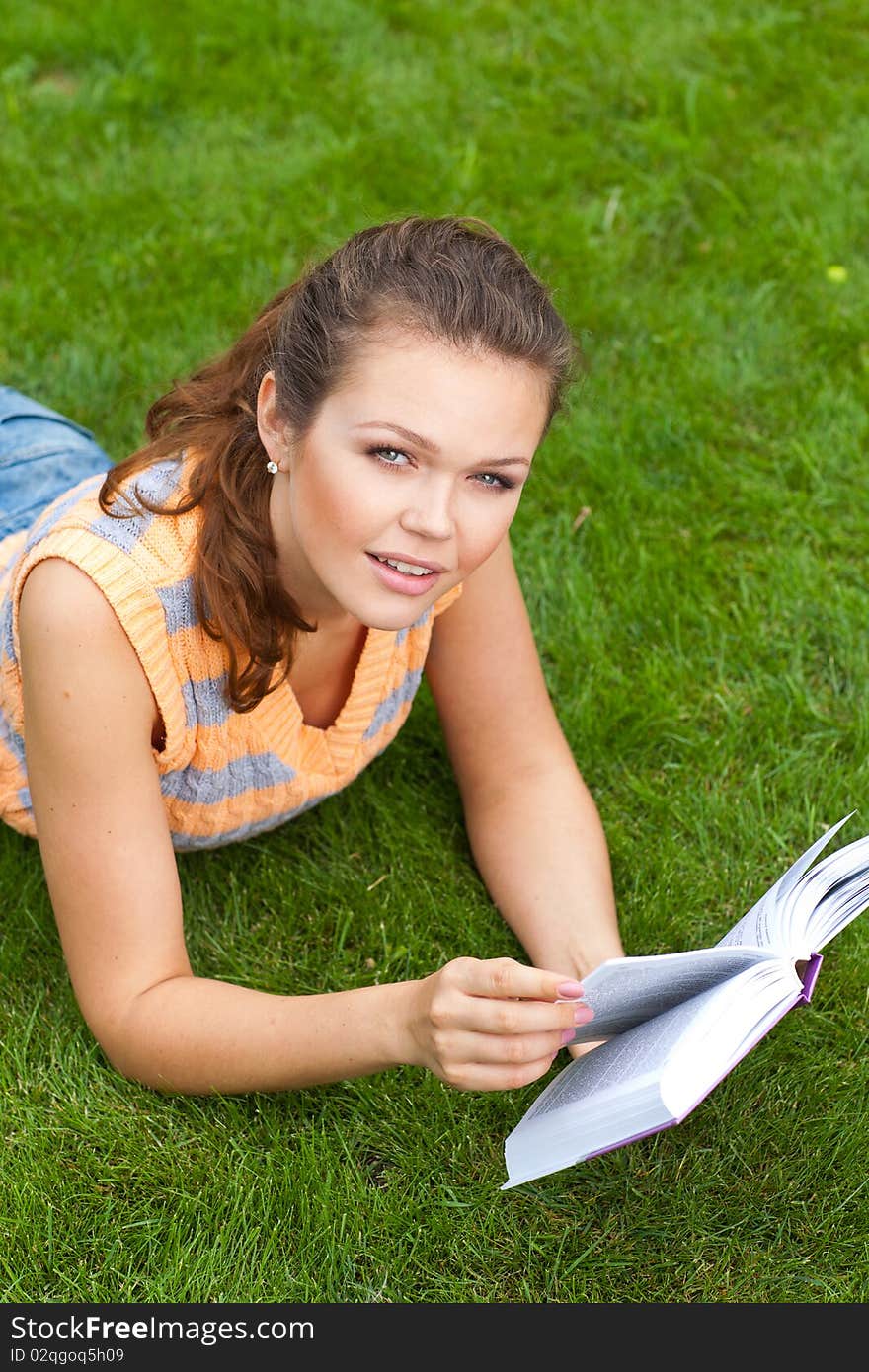 Attractive young adult reading a book on grass. Attractive young adult reading a book on grass