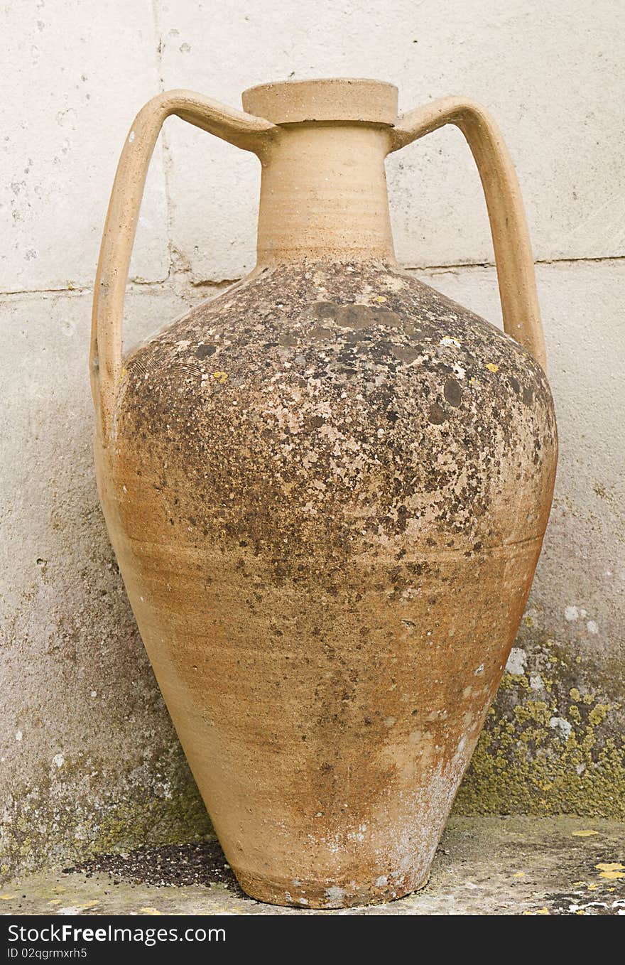 Ancient clay urn standing outside by grungy wall. Ancient clay urn standing outside by grungy wall