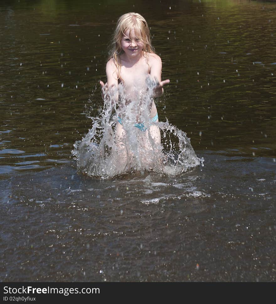 Little girl splashes with water in river