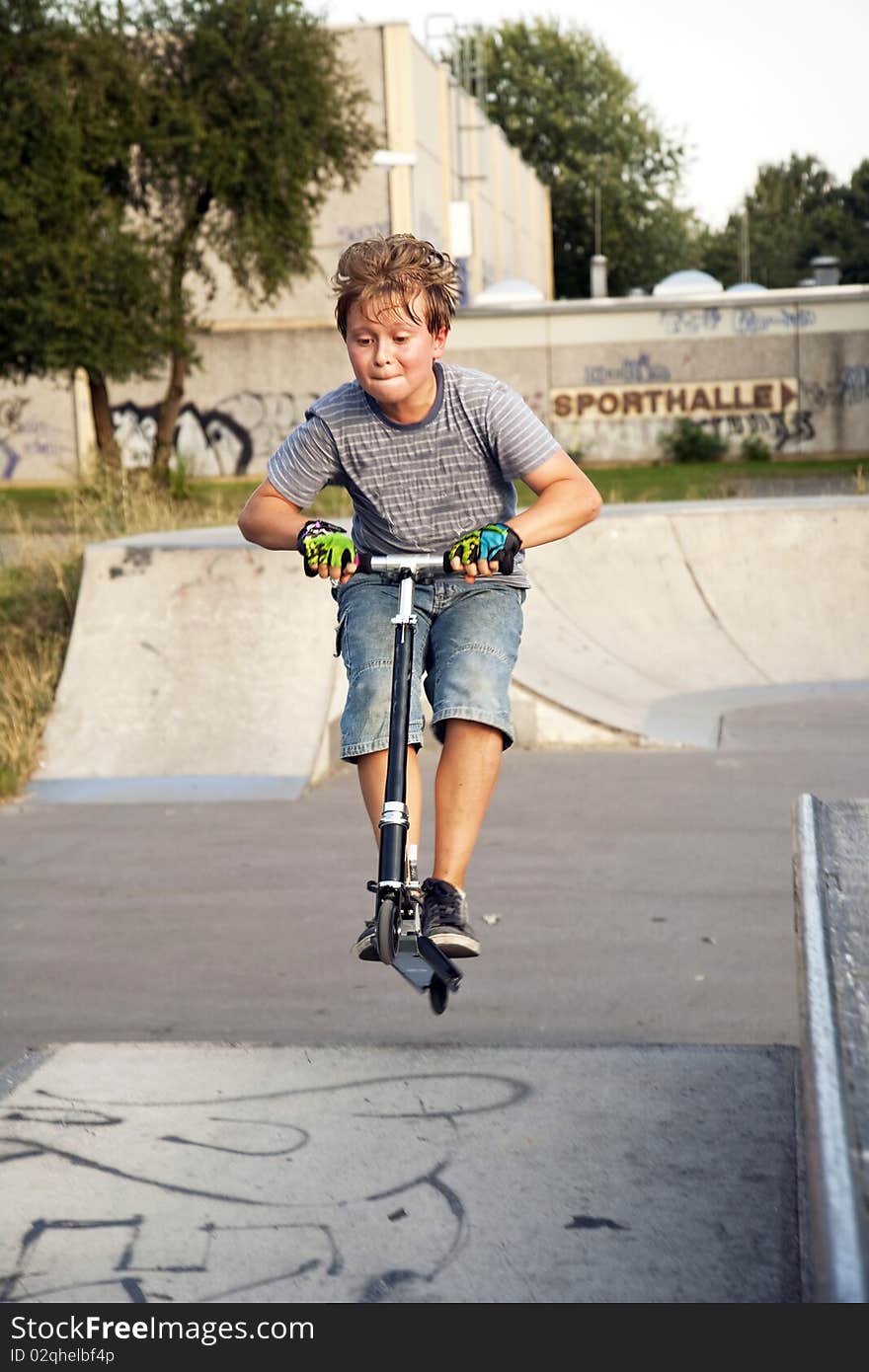 Boy riding scooter at a skate park