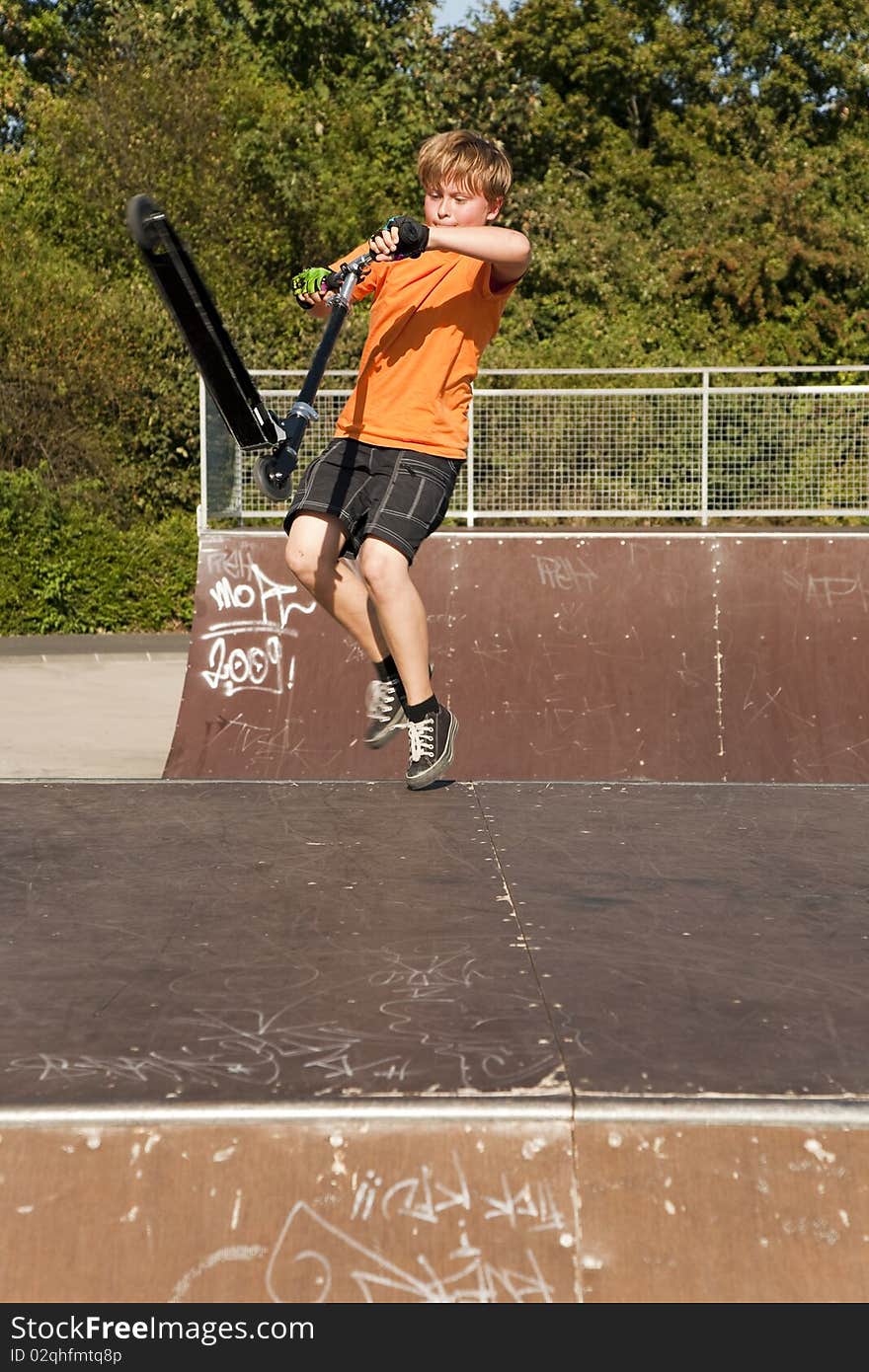 Boy with scooter at the skate parc going airborne