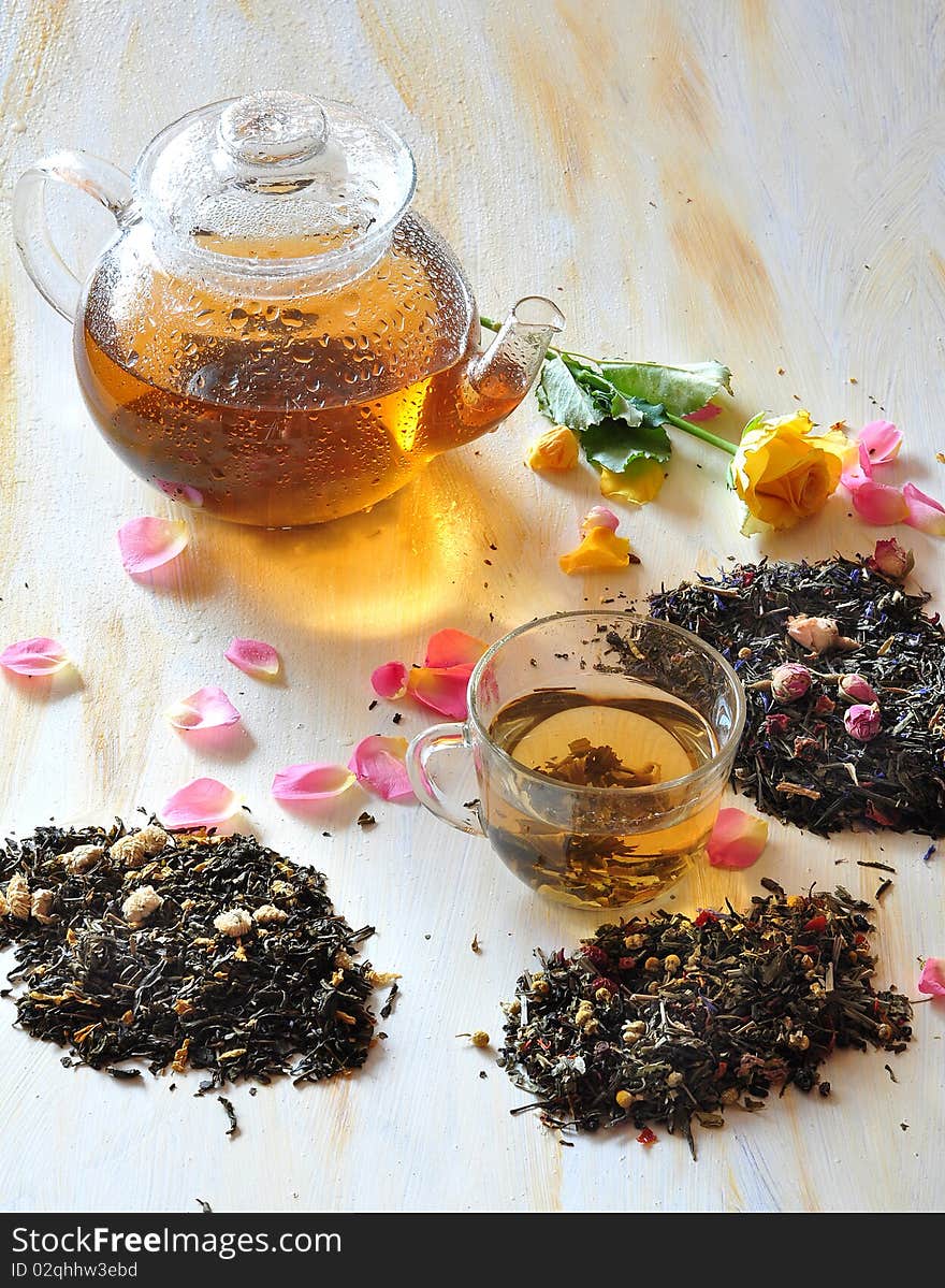 Tea is brewed in a glass tea-pot, alongside cup with tea, petals of roses and dry tea coupage. Tea is brewed in a glass tea-pot, alongside cup with tea, petals of roses and dry tea coupage