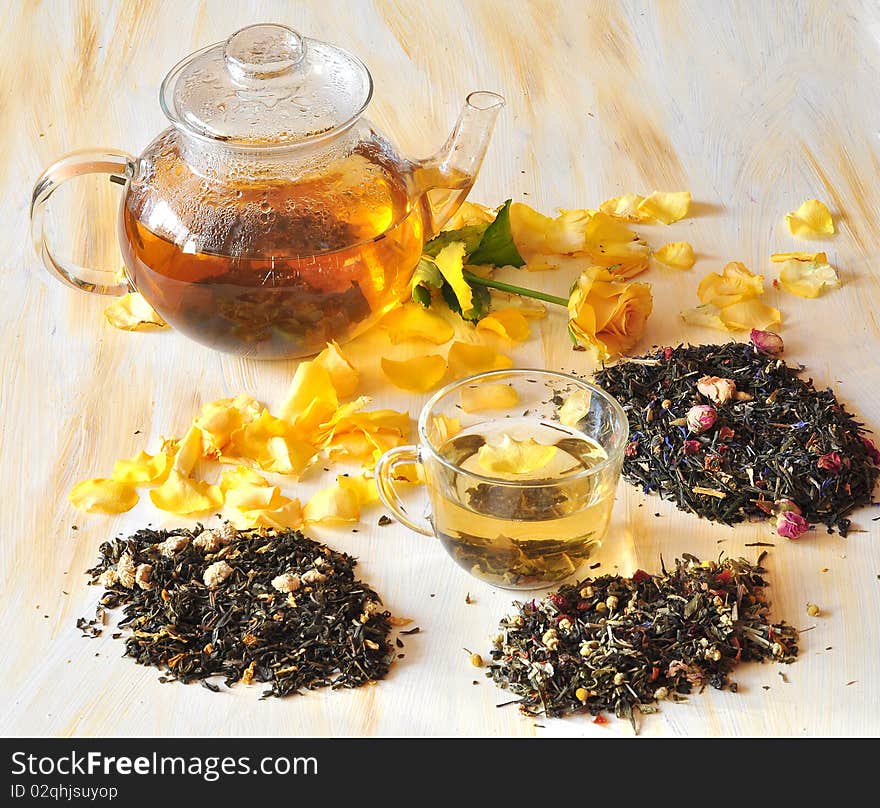 Tea is brewed in a glass tea-pot, alongside cup with tea, petals of roses and dry tea coupage. Tea is brewed in a glass tea-pot, alongside cup with tea, petals of roses and dry tea coupage