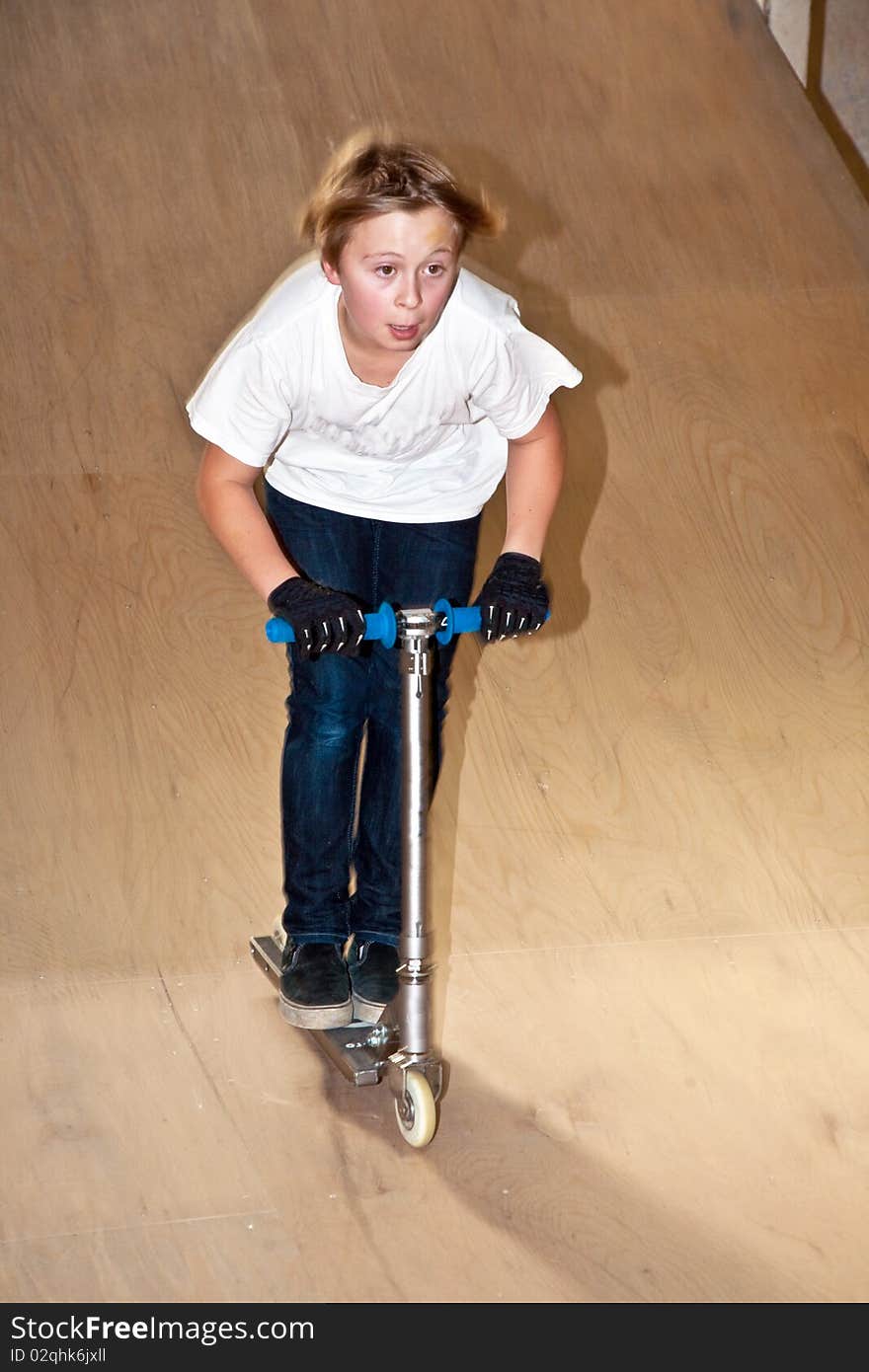 Boy is scooting with his scooter in a indoor hall. Boy is scooting with his scooter in a indoor hall