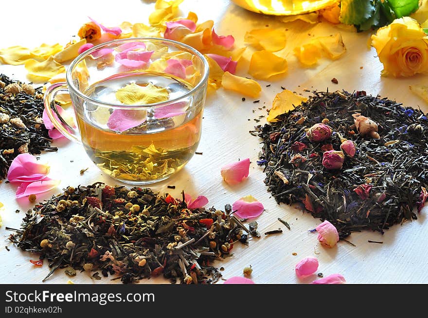 Tea is brewed in a glass cup, alongside dry tea and petals of roses. Tea is brewed in a glass cup, alongside dry tea and petals of roses