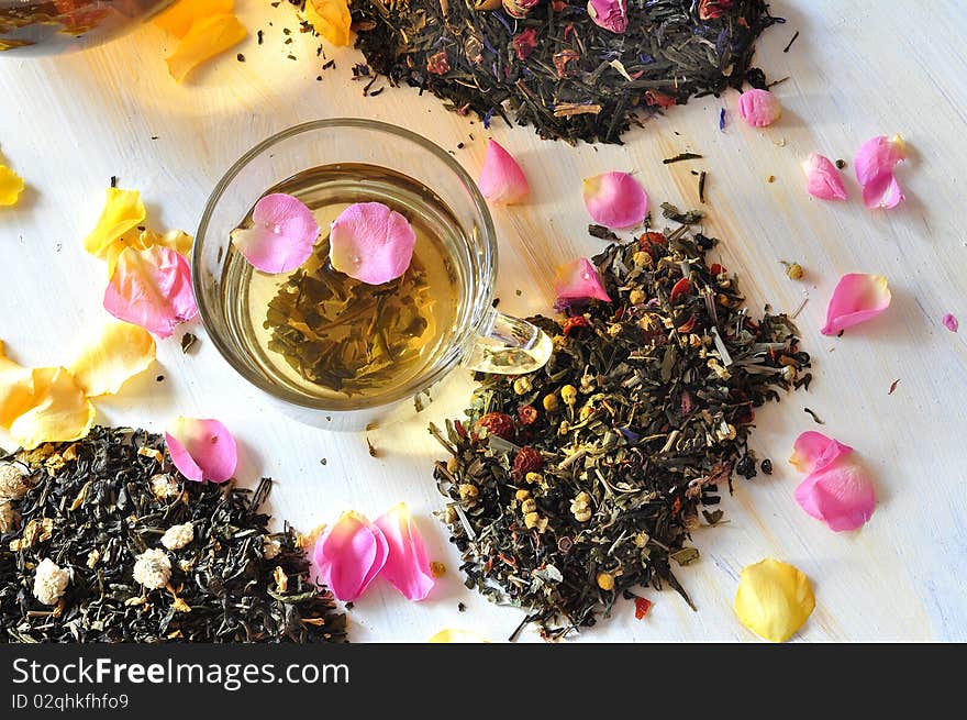 Tea is brewed in a glass cup, alongside dry tea and petals of roses. Tea is brewed in a glass cup, alongside dry tea and petals of roses