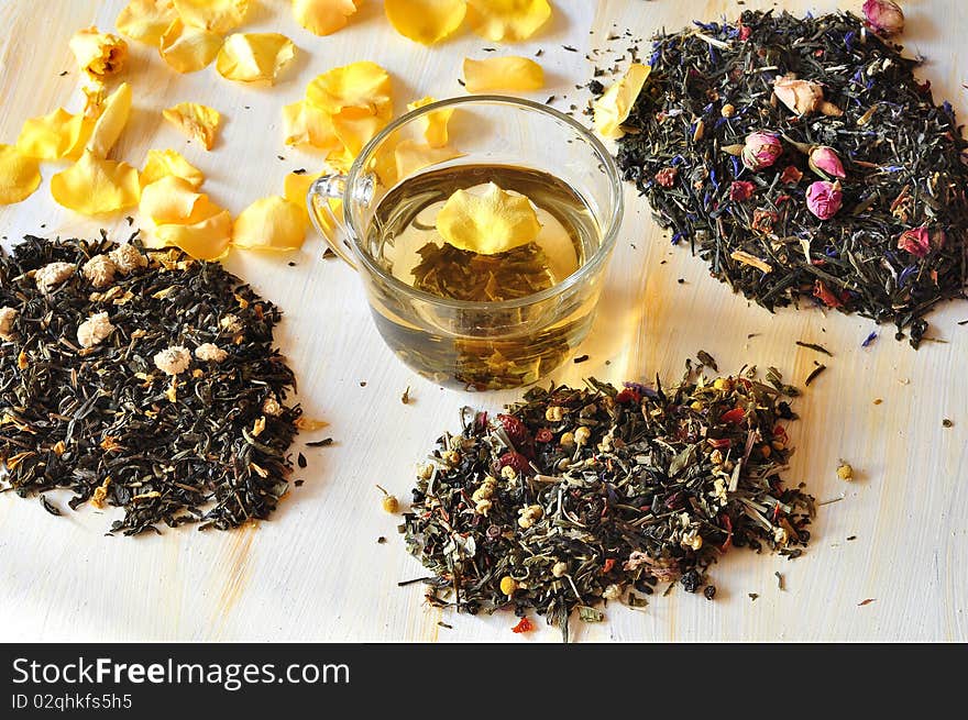 Tea is brewed in a glass cup, alongside dry tea and petals of roses. Tea is brewed in a glass cup, alongside dry tea and petals of roses