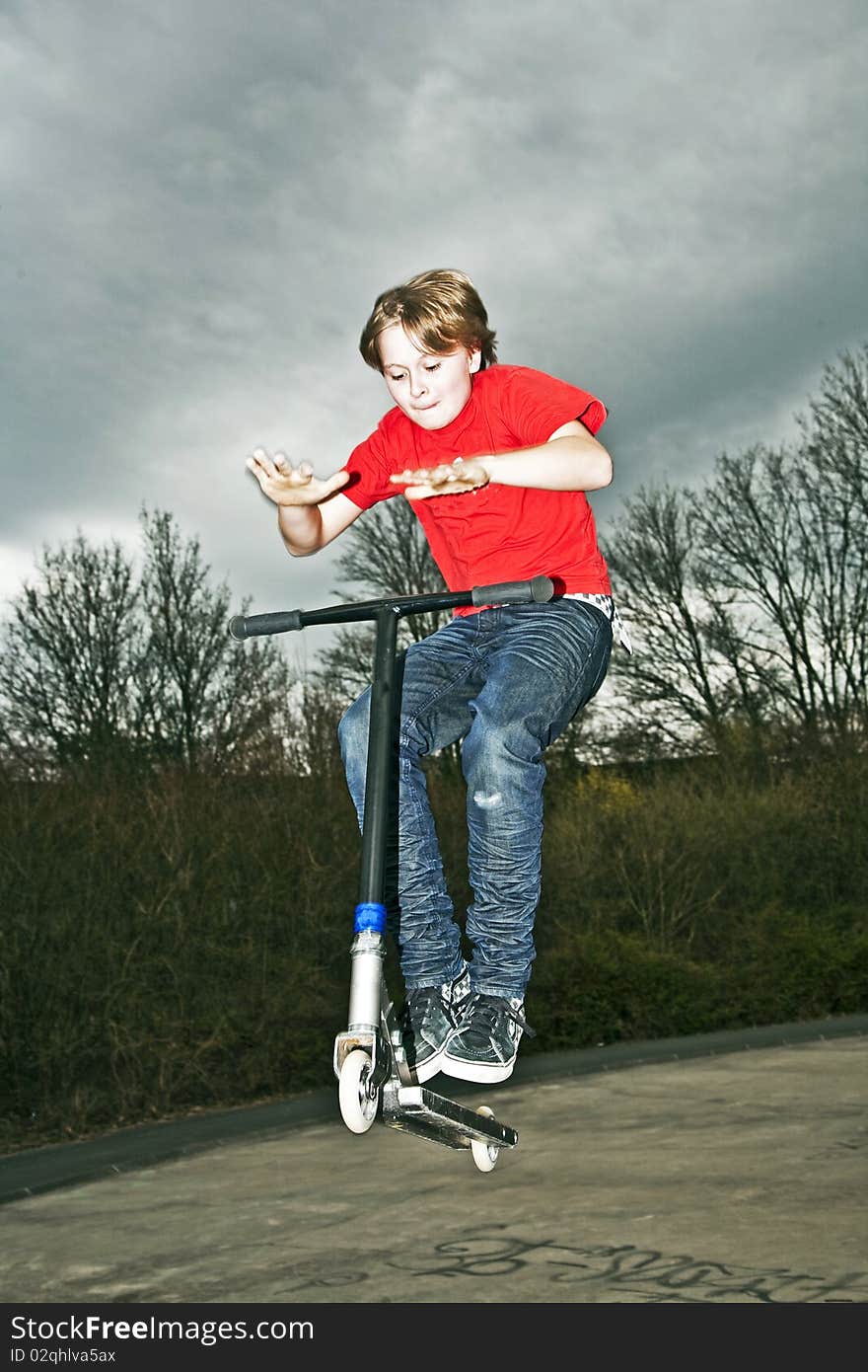 Boy riding a scooter going airborne at a scooter park. Boy riding a scooter going airborne at a scooter park