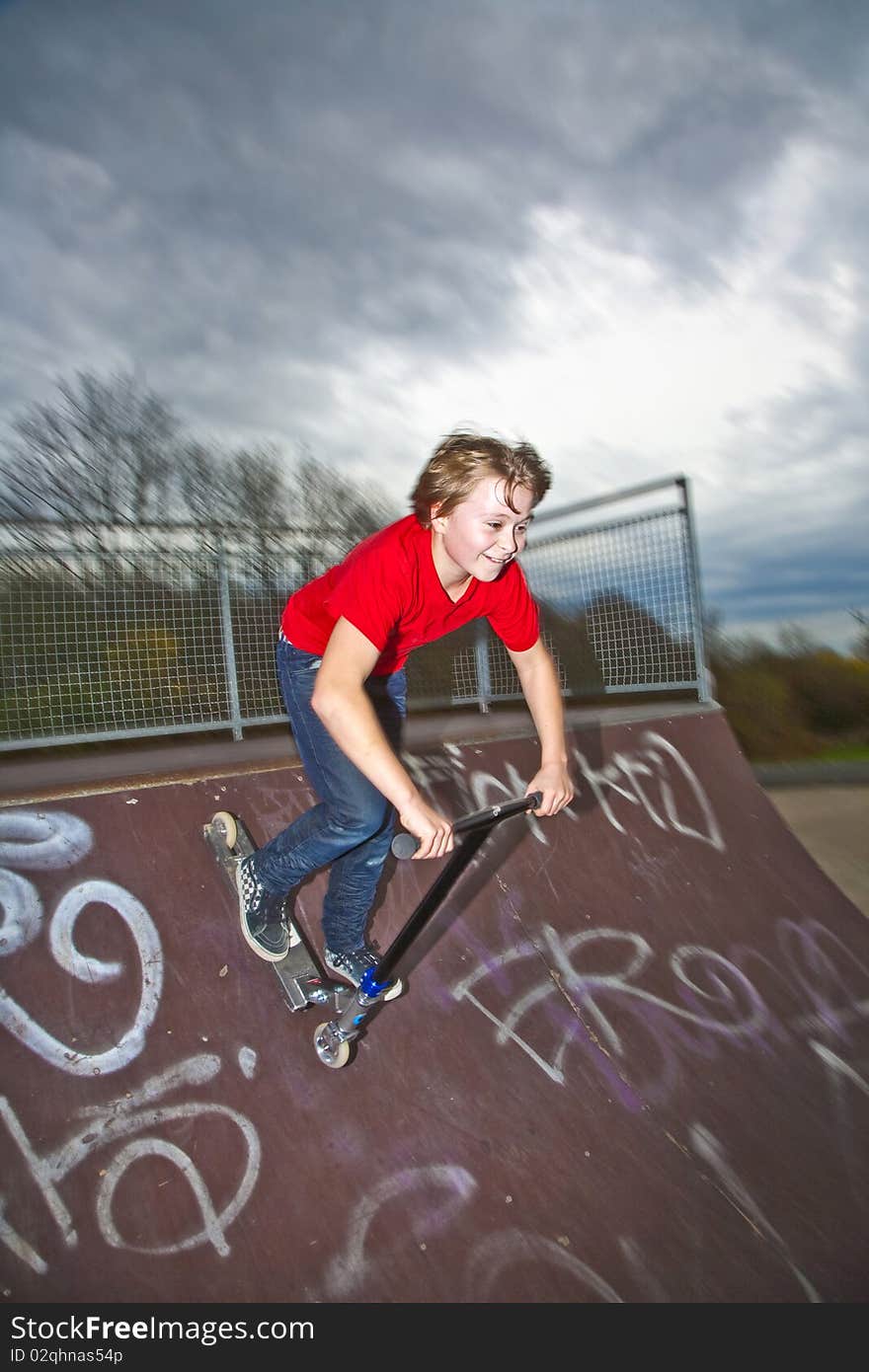 Boy riding a scooter going airborne at a scooter park. Boy riding a scooter going airborne at a scooter park