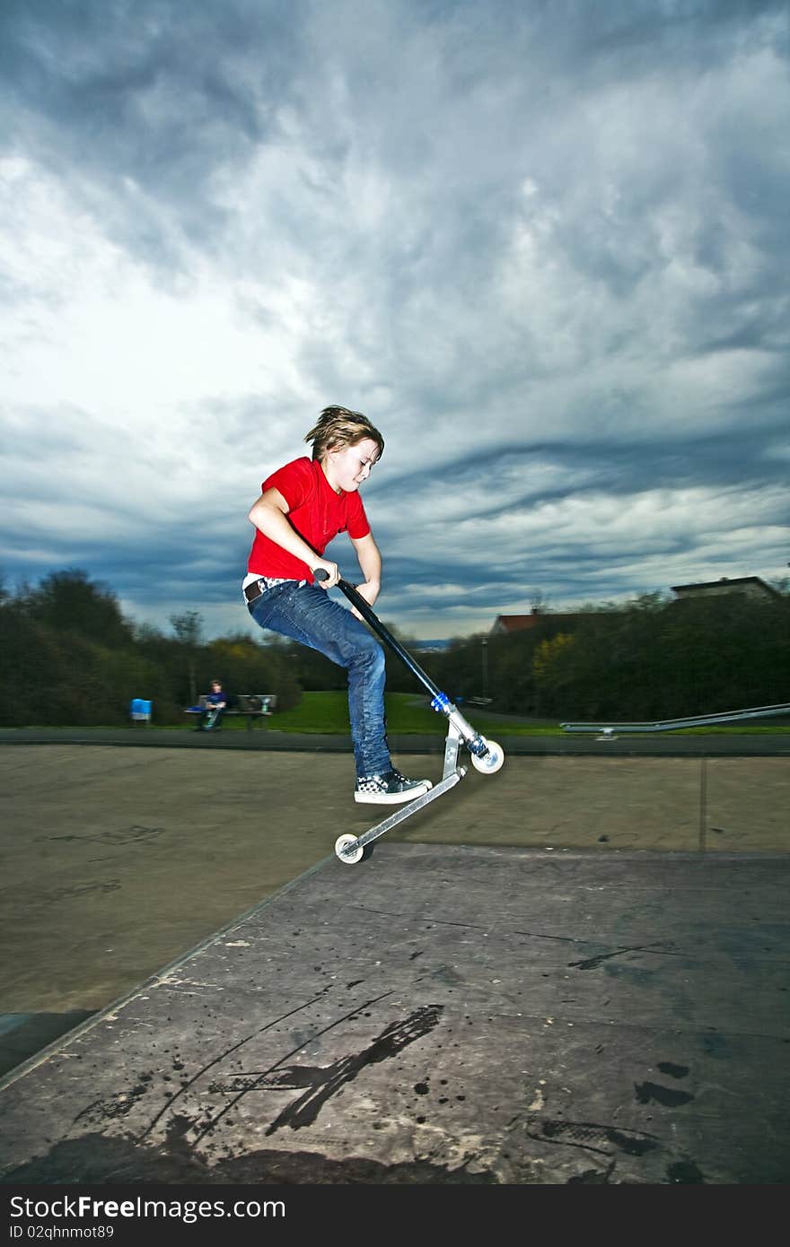 Boy riding a scooter going airborne at a scooter park. Boy riding a scooter going airborne at a scooter park