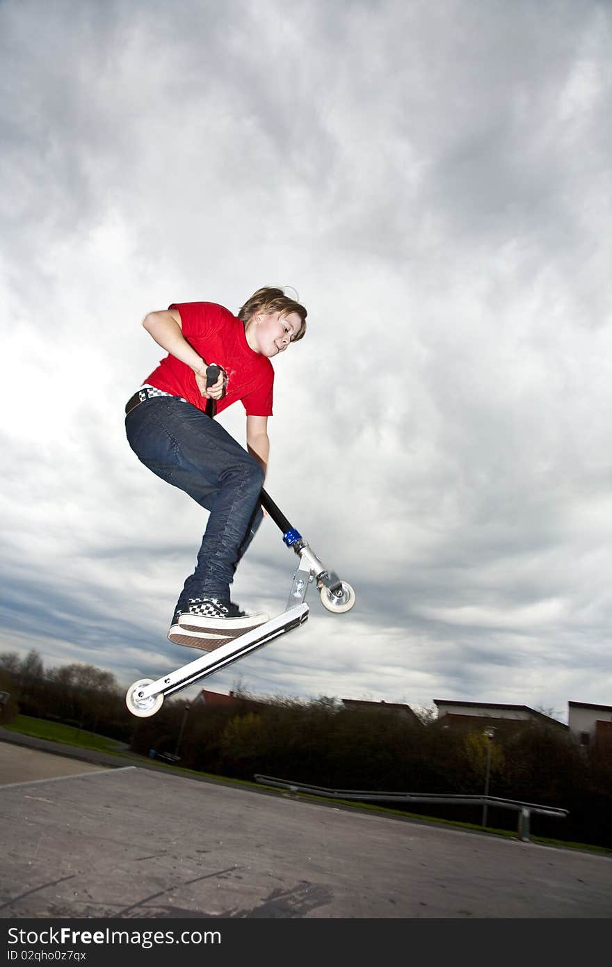 Boy riding a scooter going airborne at a scooter park. Boy riding a scooter going airborne at a scooter park