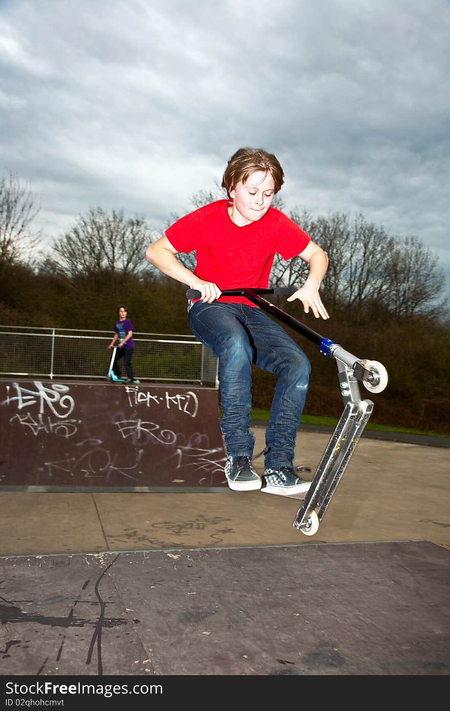 Boy riding a scooter gone airborne on a scooter park. Boy riding a scooter gone airborne on a scooter park