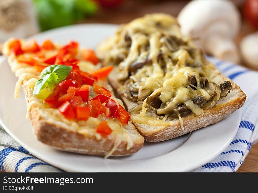 Close up of toasts with cheese,pepper and mushrooms in a rustic dish. Close up of toasts with cheese,pepper and mushrooms in a rustic dish