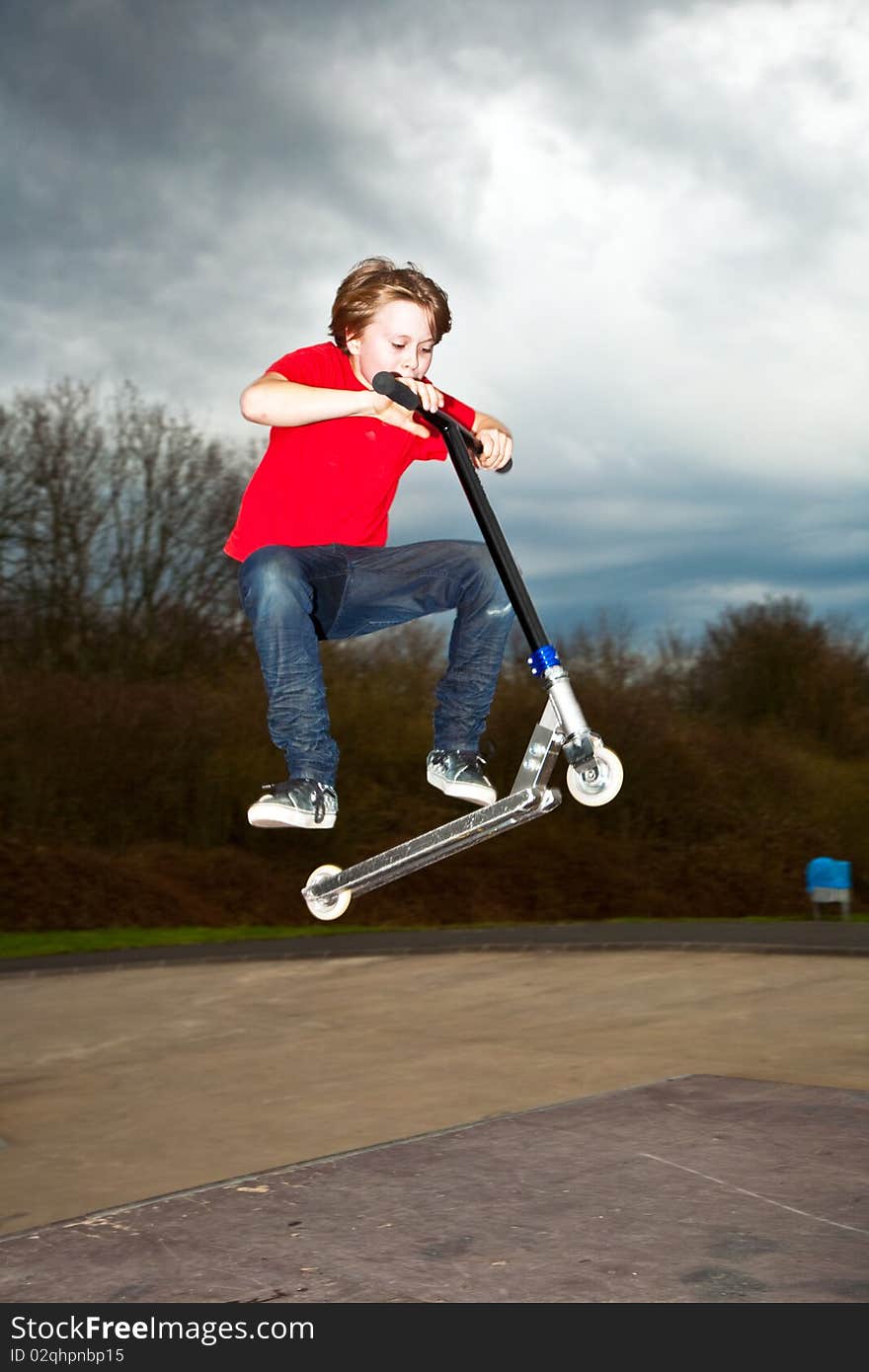 Boy riding a scooter gone airborne on a scooter park. Boy riding a scooter gone airborne on a scooter park