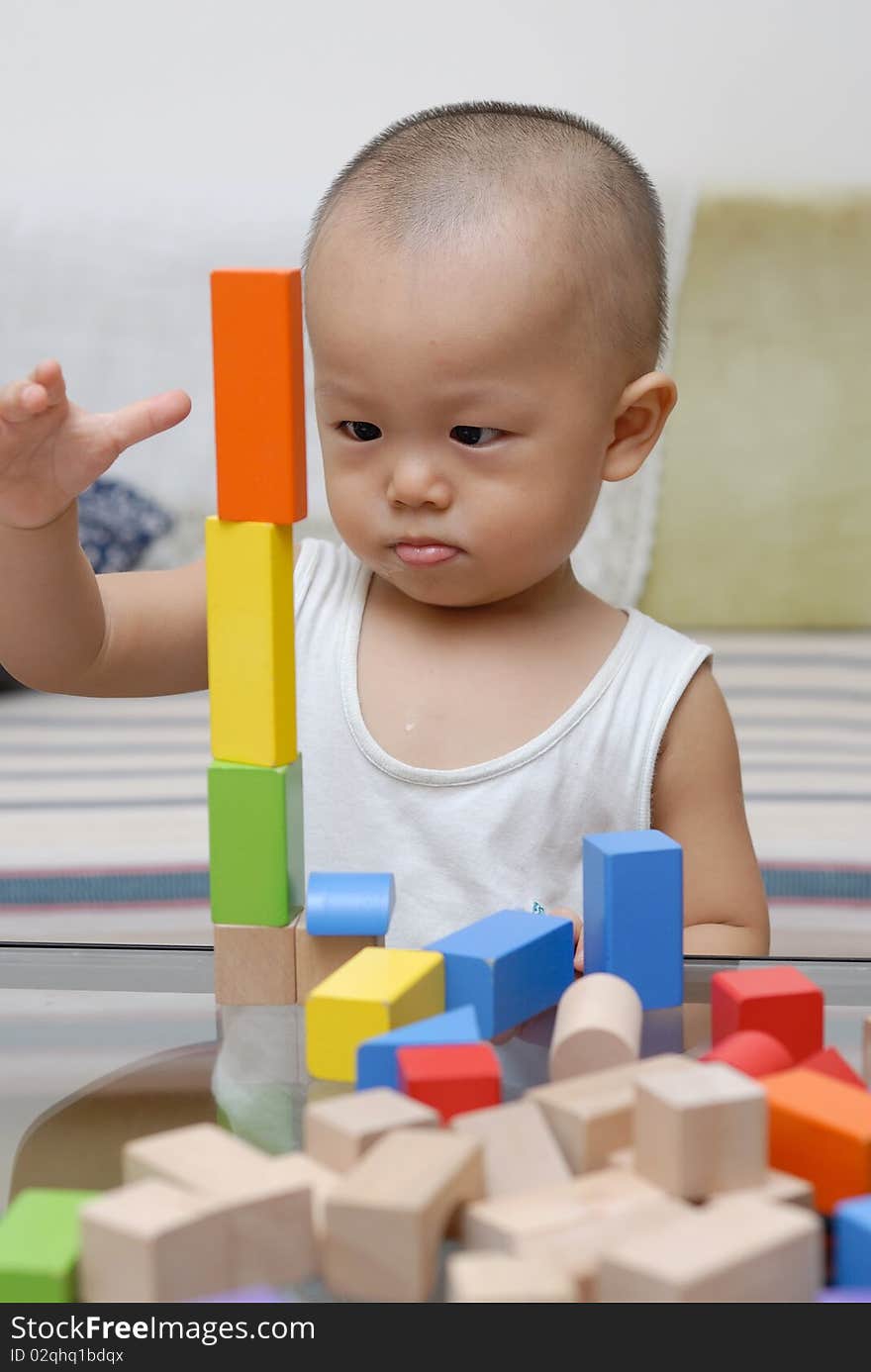 A chinese child is playing with wooden toy blocks in home.