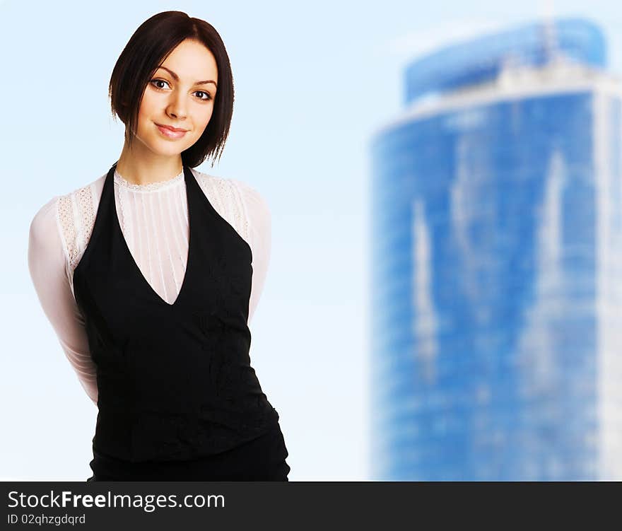 Young beautiful businesswoman against blue sky and modern building