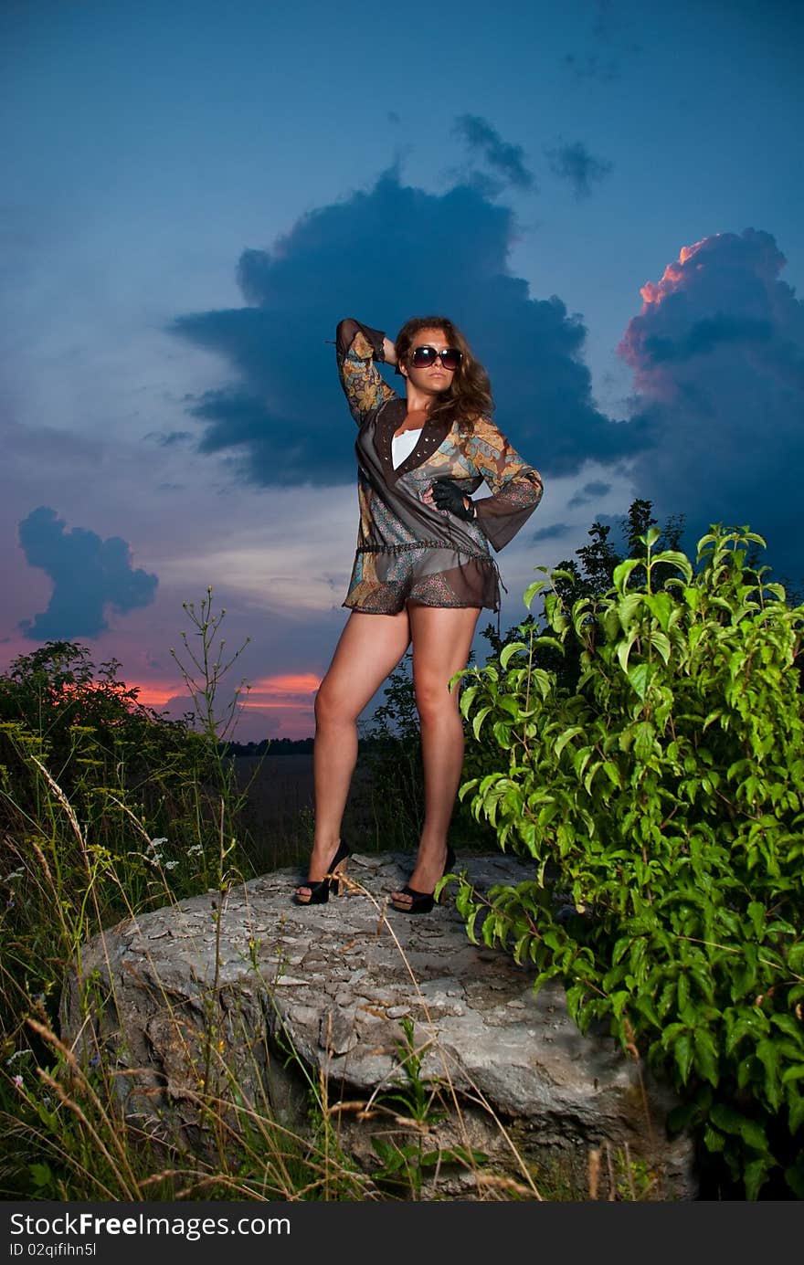 Young woman in sunglasses standing at sunset rock. Young woman in sunglasses standing at sunset rock