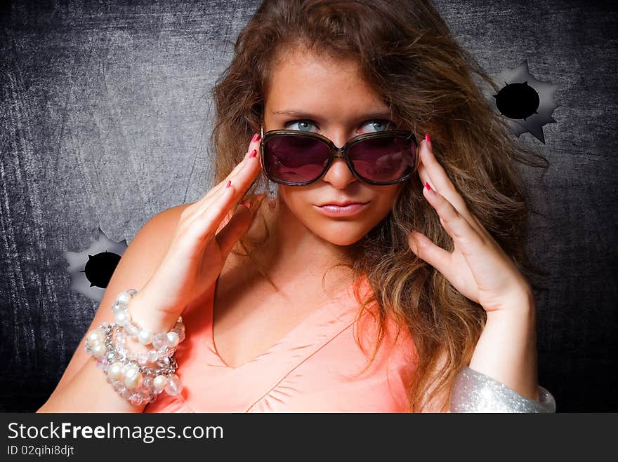 Stylish woman in sunglasses at the metallic wall with holes from bullets. Stylish woman in sunglasses at the metallic wall with holes from bullets