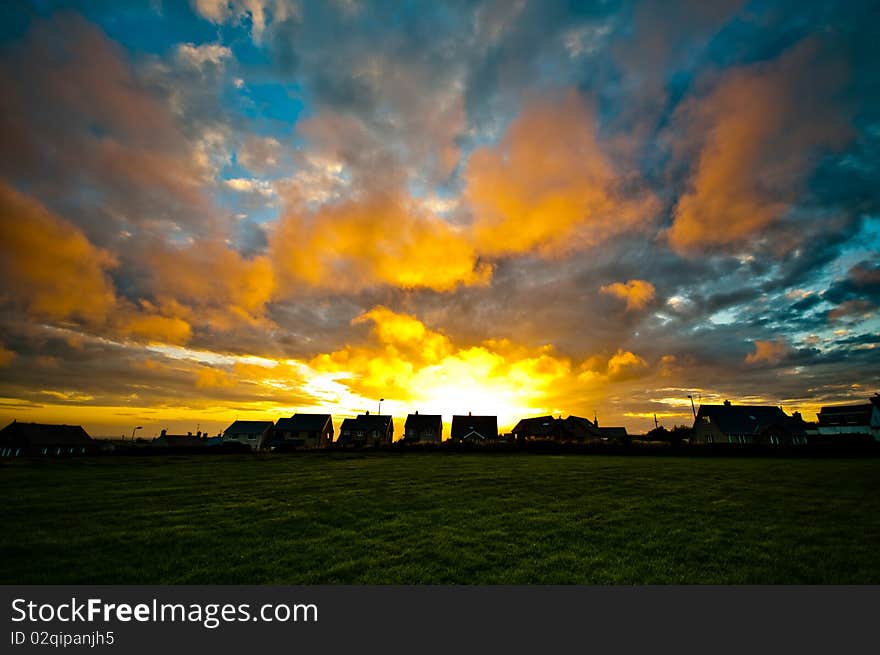 Colourful sunset with houses and field