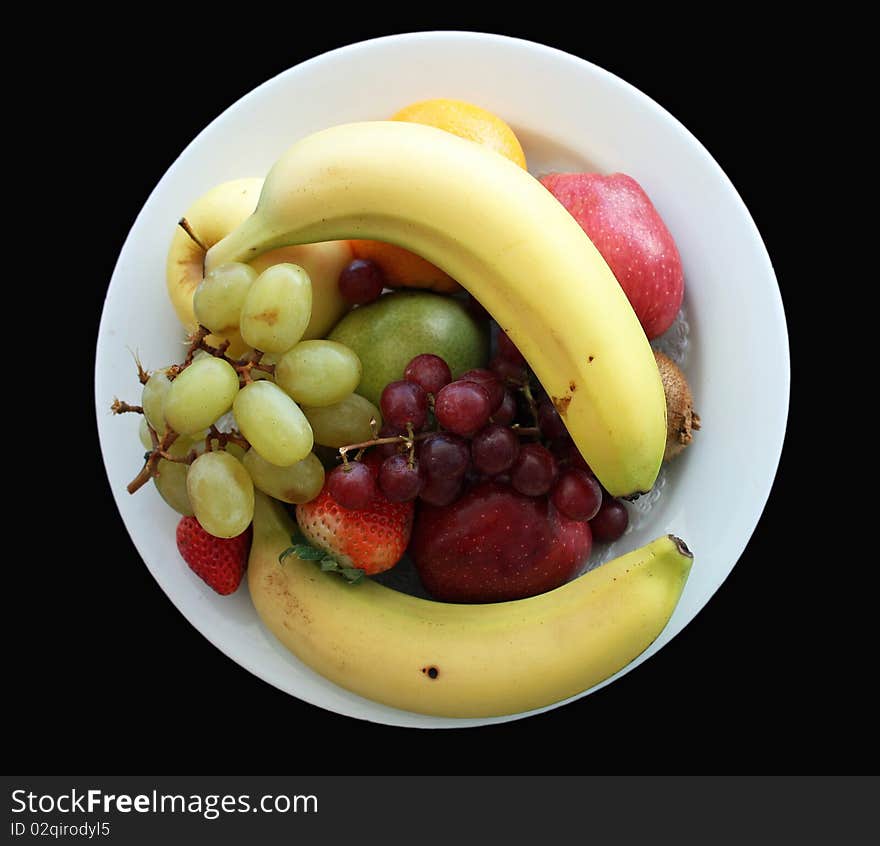 An assortment of fuit on a white plate with black background. An assortment of fuit on a white plate with black background.