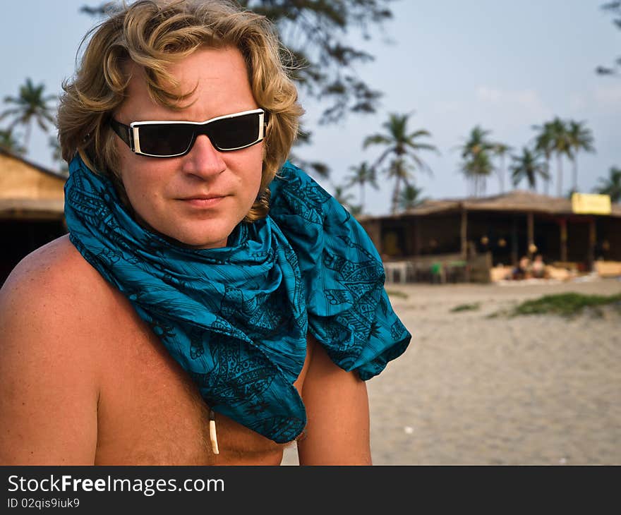 Blonde man against a tropical palm on a beach. Blonde man against a tropical palm on a beach