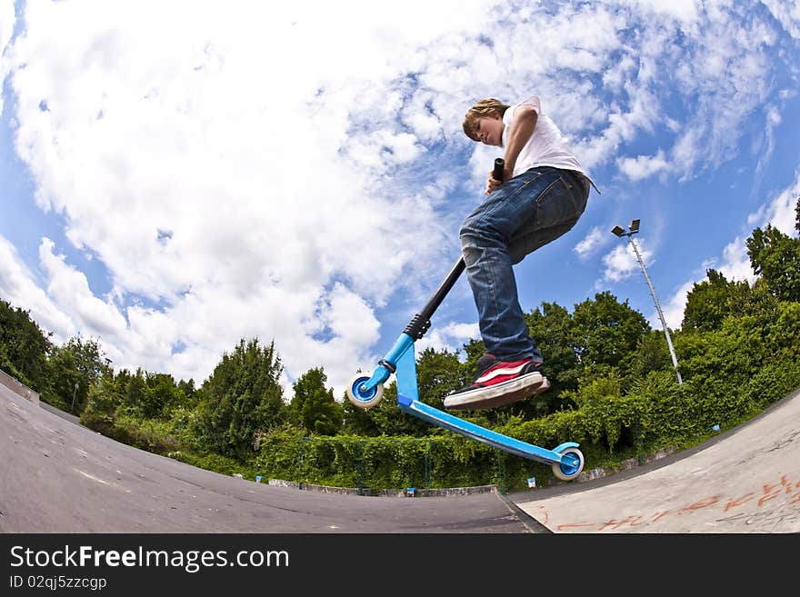 Young boy with scooter is going airborne