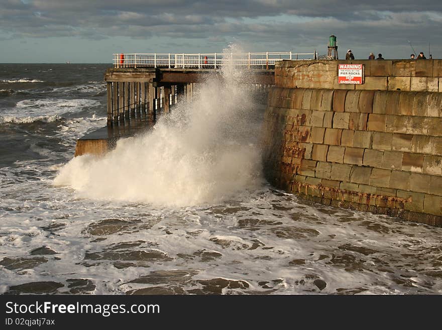 North Sea waves crashing under Whitby Pier in North Yorkshire, England. North Sea waves crashing under Whitby Pier in North Yorkshire, England