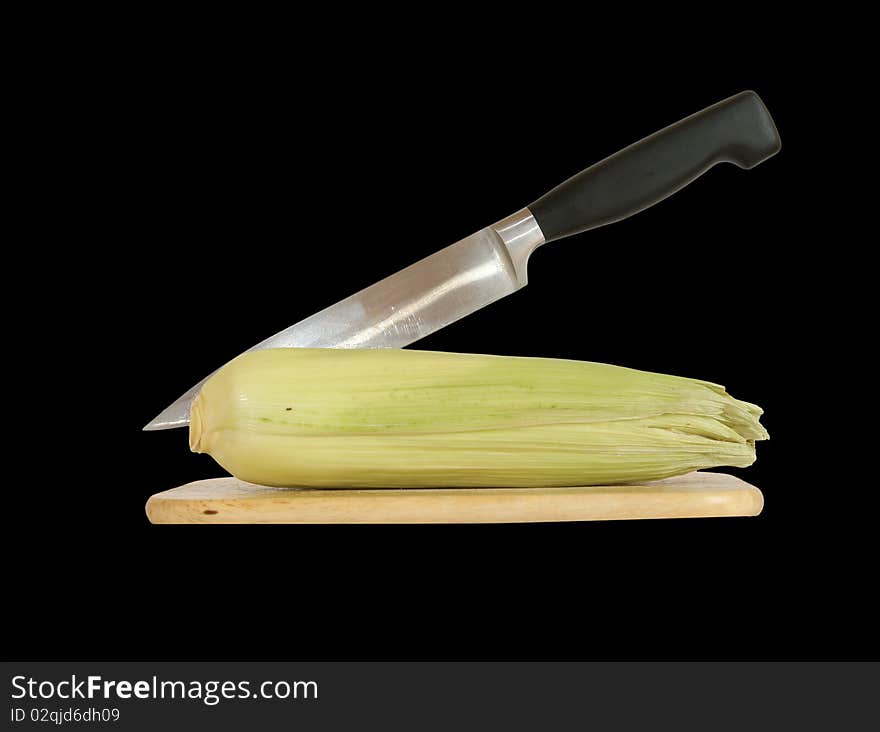 Still life with a natural corn cob with a knife and cutting board. In isolation