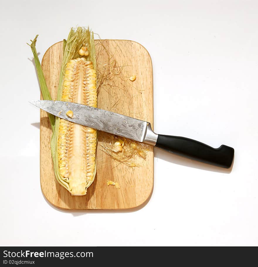 Still life with a natural corn cob with a knife and cutting board. In isolation