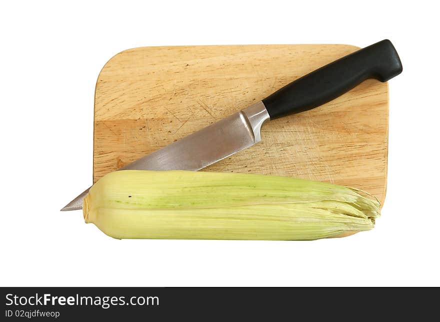 Still life with a natural corn cob with a knife and cutting board. In isolation