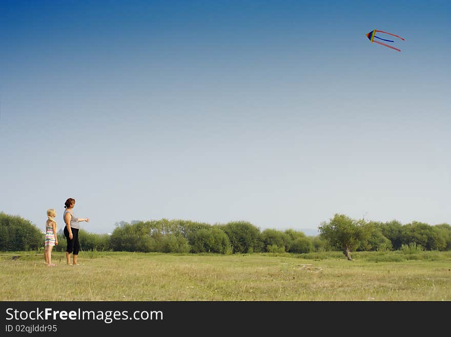 The grand daughter and the grandmother start a kite on a meadow