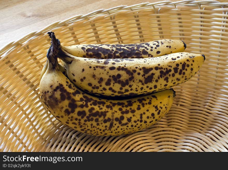 Ripe spotty bananas in a wicker basket. Ripe spotty bananas in a wicker basket