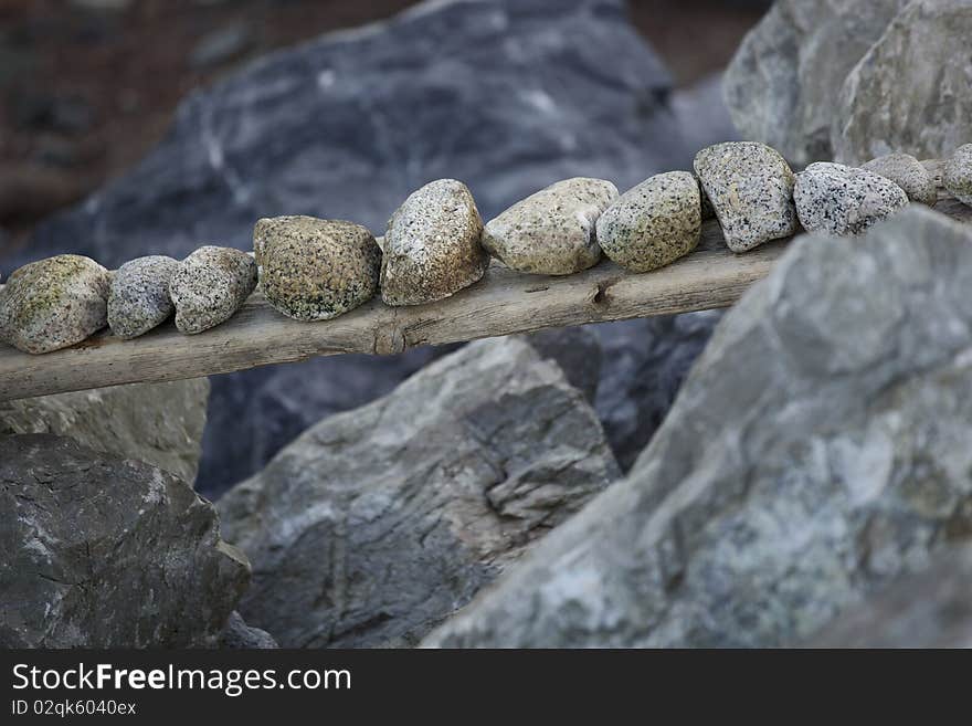 A group of small rocks balanced on a plank over larger rocks. A group of small rocks balanced on a plank over larger rocks