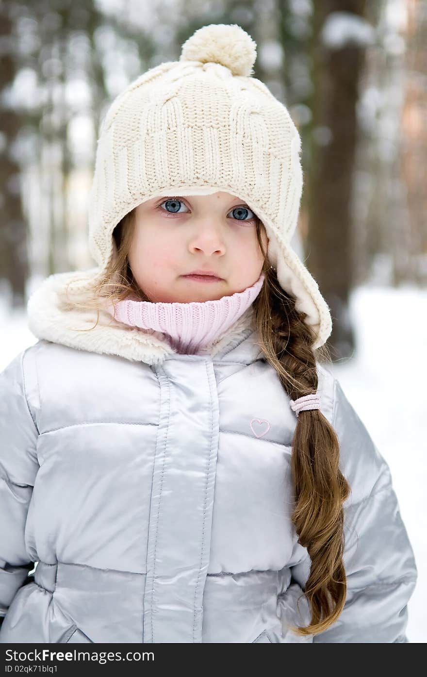 Toddler girl in warm white hat in winter forest with long plait. Toddler girl in warm white hat in winter forest with long plait