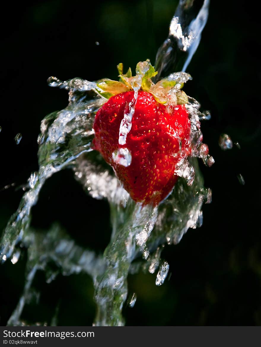 Strawberry in a stream of water on a dark background