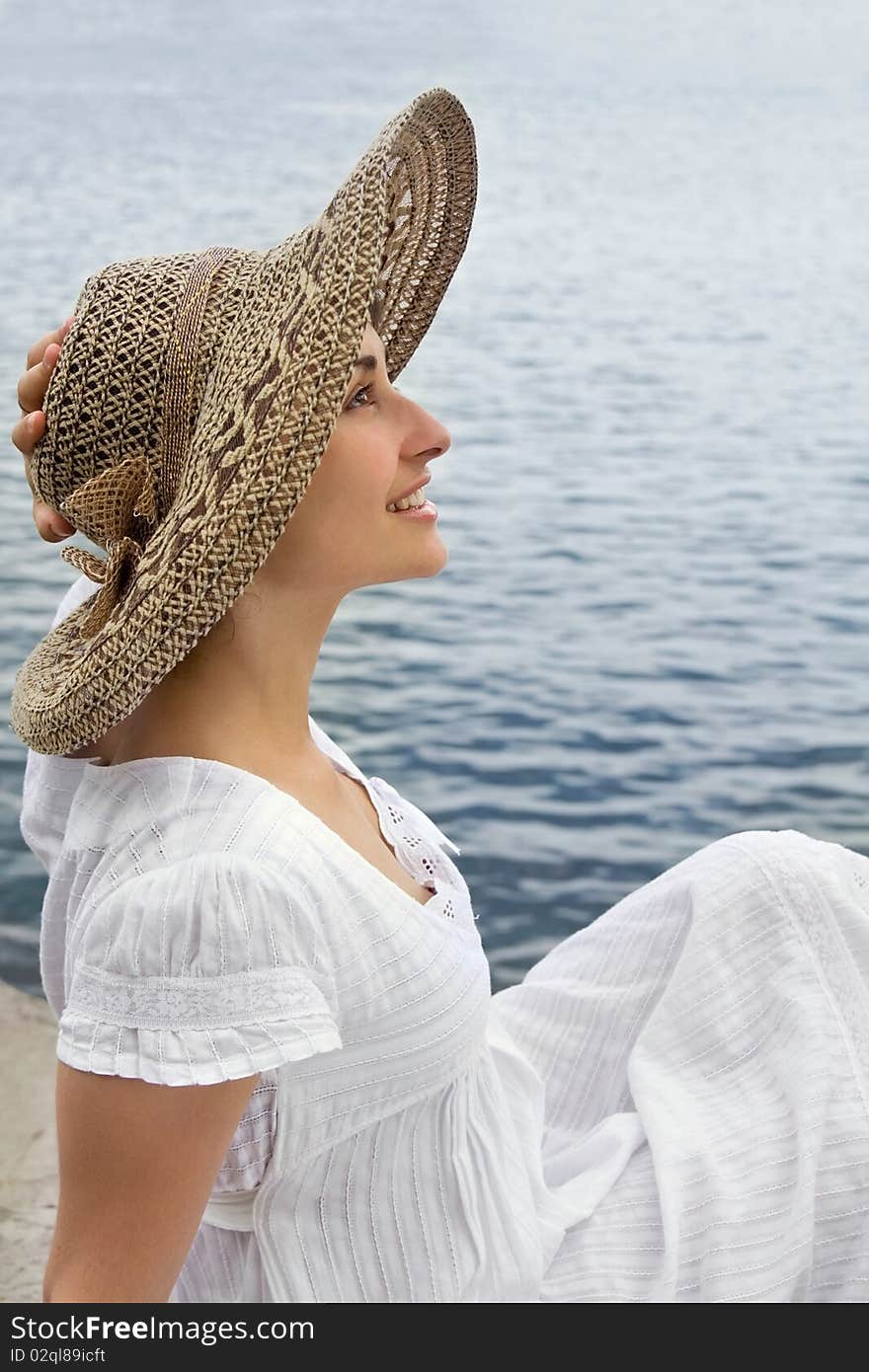 Happy young girl in the bonnet near the sea