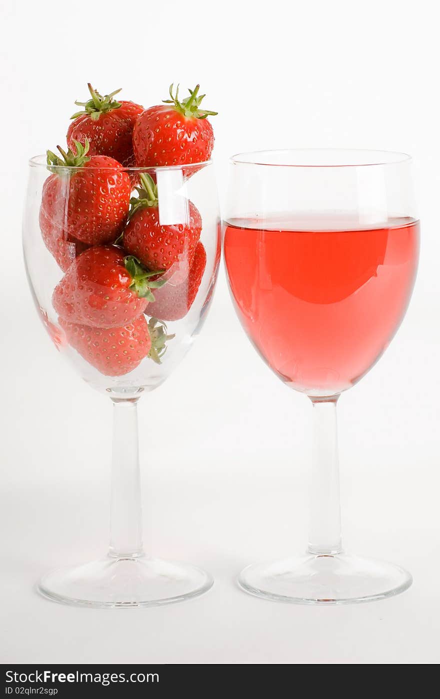 A vertical image of two wine glasses one with wine and the other filled with fresh strawberries. A vertical image of two wine glasses one with wine and the other filled with fresh strawberries