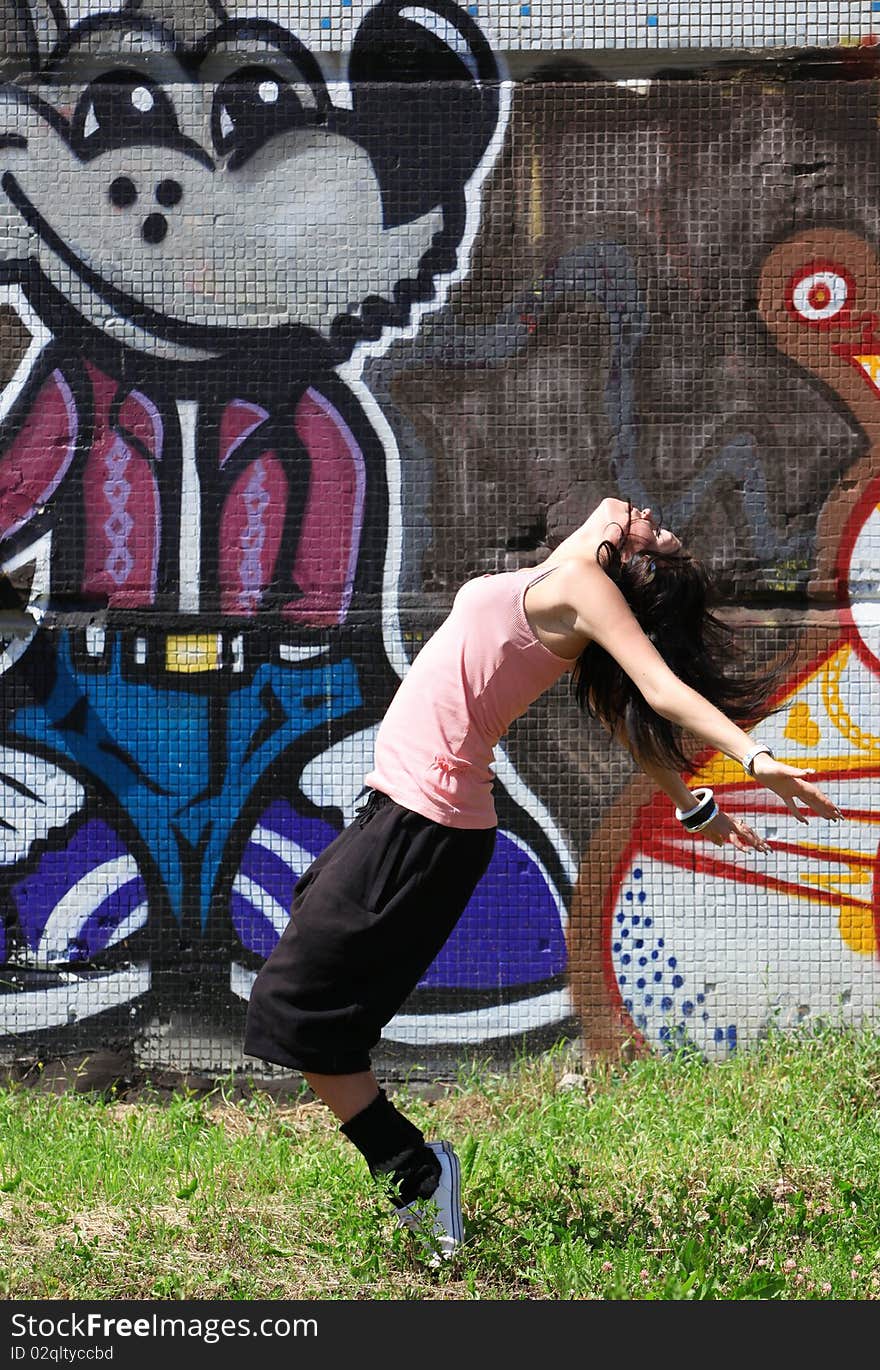 Woman modern dancer in city against graffiti wall