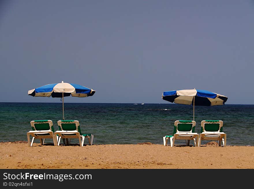 Two pairs of beach beds with open parasols