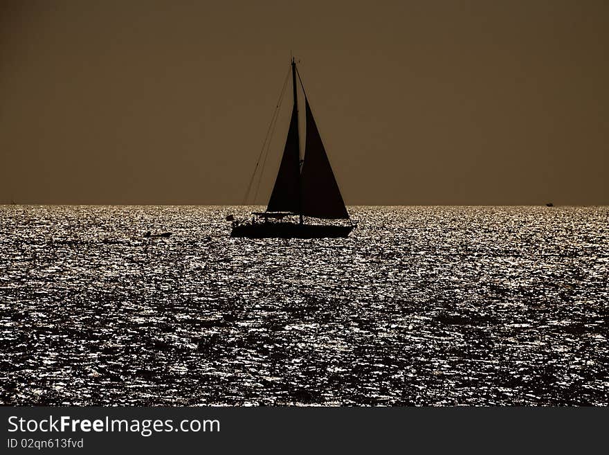 Black silhouette of the sailboat against the eveing sun on the sea. Black silhouette of the sailboat against the eveing sun on the sea