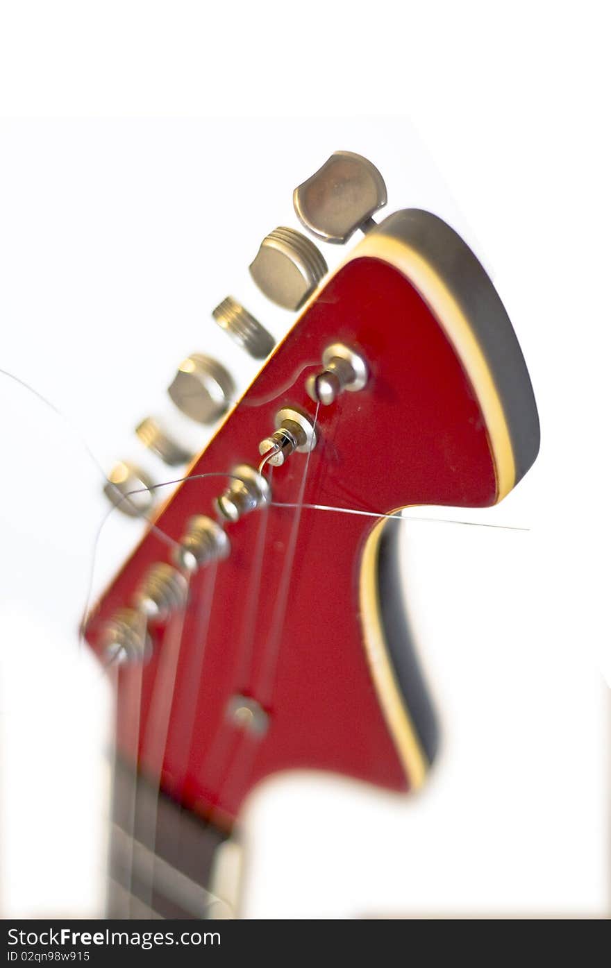 Headstock of an electric guitar close up. On a white background. Selective focus on the string. Blur. Headstock of an electric guitar close up. On a white background. Selective focus on the string. Blur.