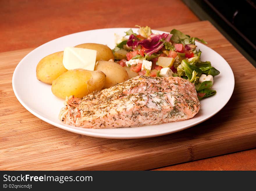 Salmon on a plate with potatoes and salad