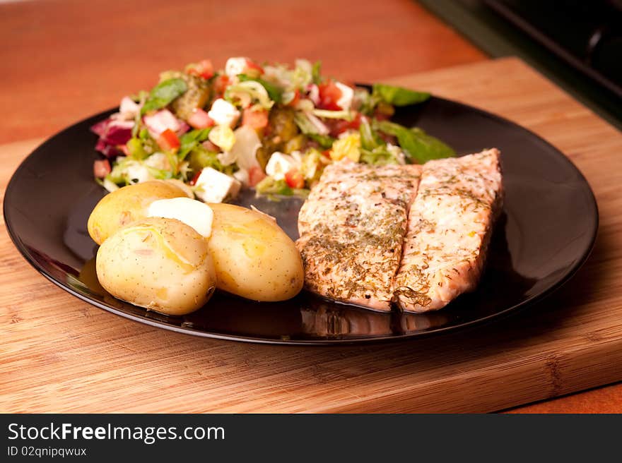 Salmon on a plate with potatoes and salad