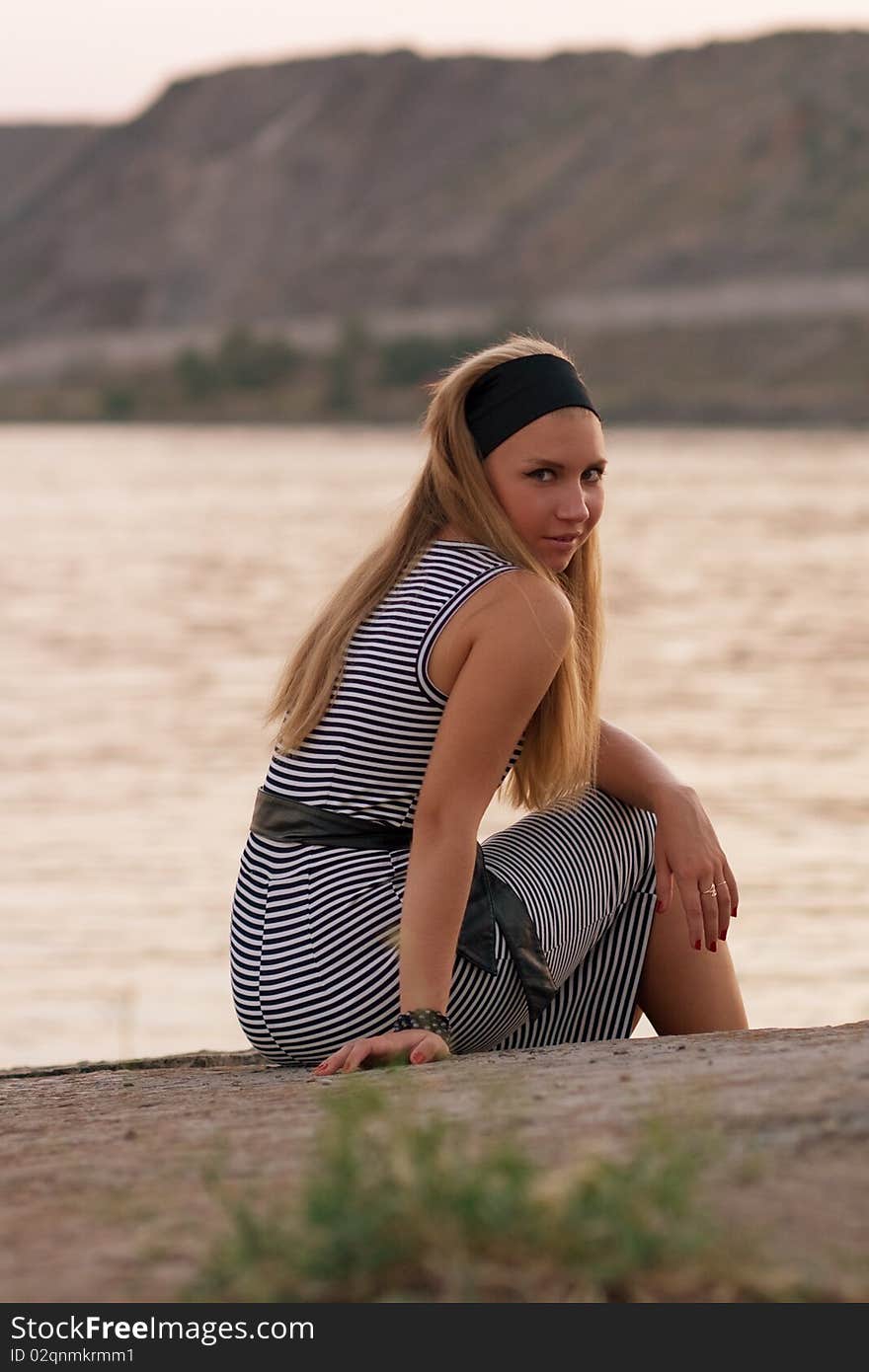 Pretty young girl sitting at the seaside