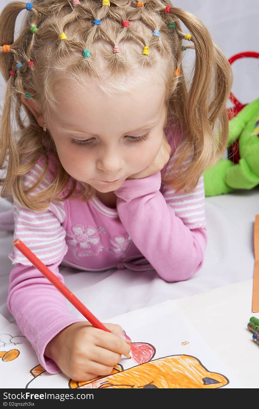 Small cute little blond girl with nice hair-dress drawing with colorful pencils  lying on floor. Small cute little blond girl with nice hair-dress drawing with colorful pencils  lying on floor