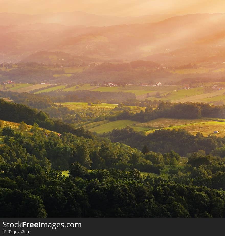 One part of a village Dragacevo in Central Serbia, picturesque sunset with orange atmosphere and white sun rays across the fields, forests and meadows of this beautiful country.