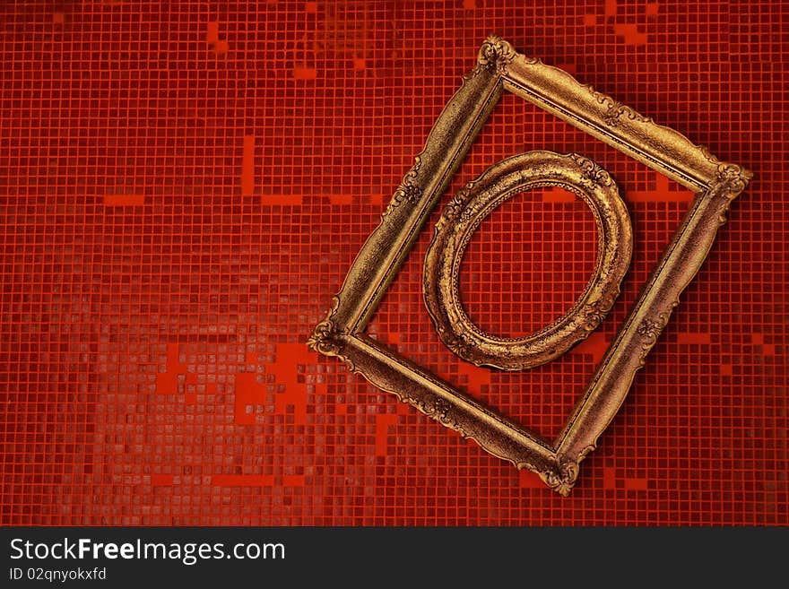 Old frames hanged on a wall covered in red tiles.